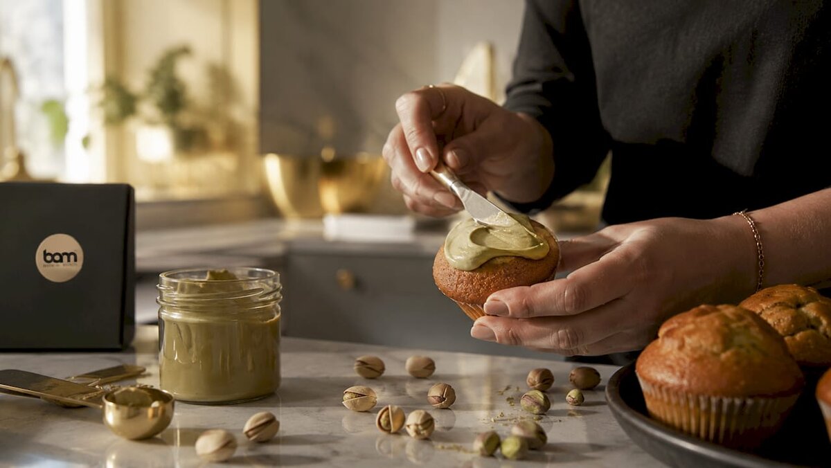 Hände, die Pistaziencreme auf einen Muffin streichen